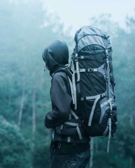 Solo hiker with large backpack in a misty forest, exploring nature's serene beauty.